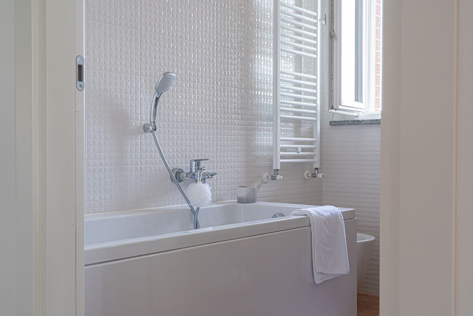 A bright bathroom with a white towel on the tub.