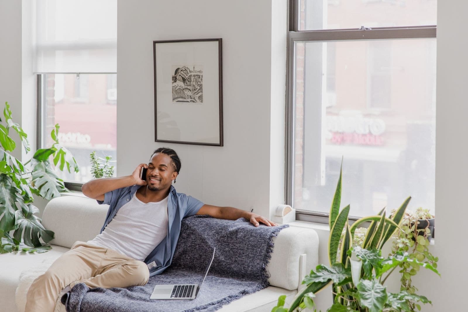 A person smiling on a sofa by a bright window.