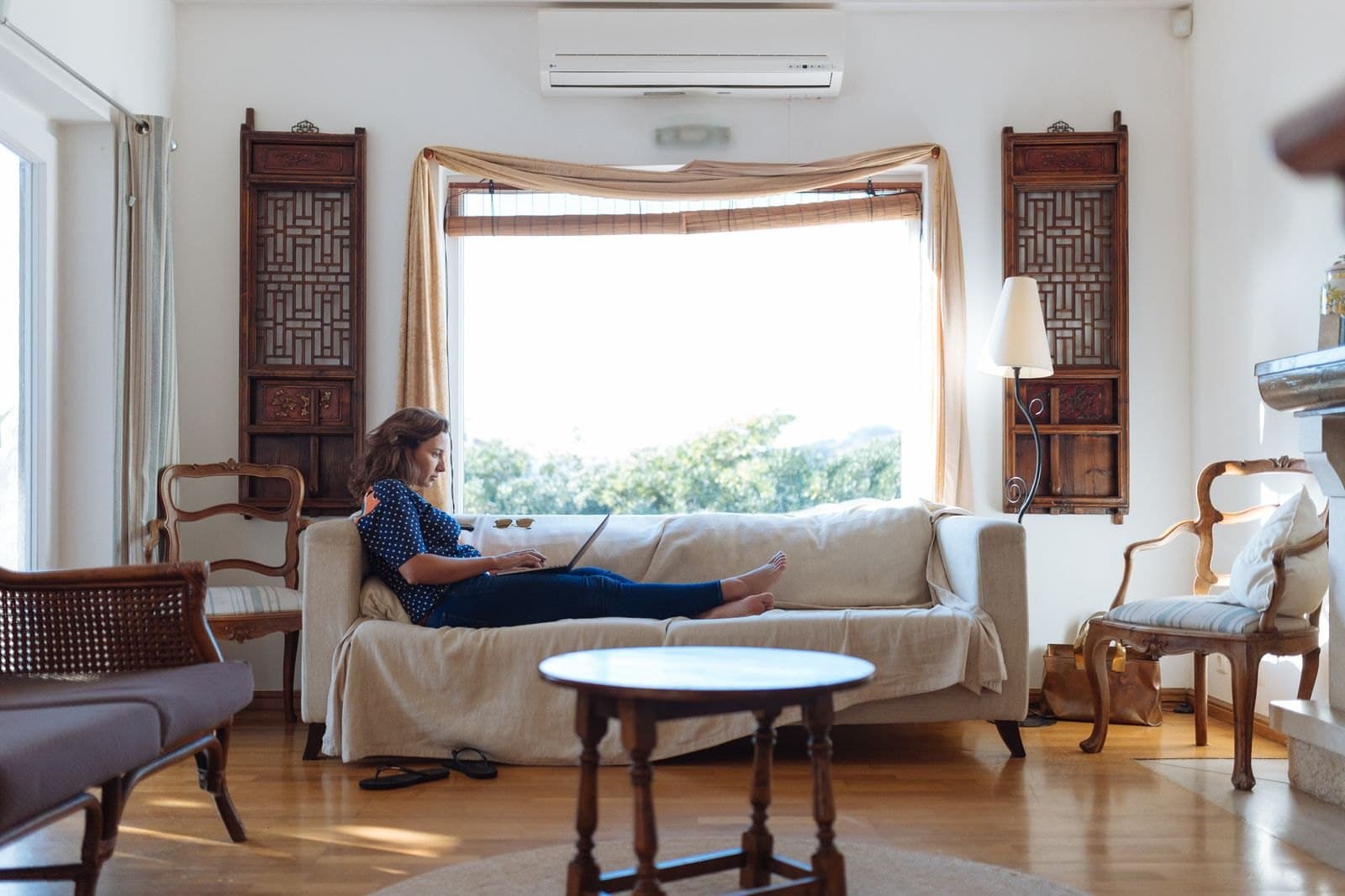 A person on a sofa in a sunlit living room.
